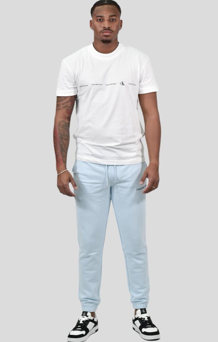 Frescura urbana: camiseta com logo branco, calça institucional azul e tênis bimaterial Calvin Klein