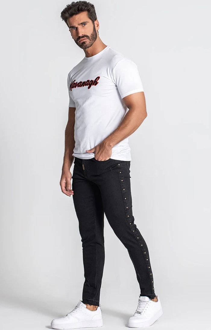 Eleganza in evidenza: T-shirt bianca dalla silhouette sontuosa, jeans lussuosi neri e sneakers basic bianche di Gianni Kavanag